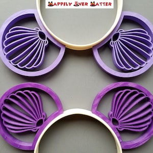 May include: Purple Minnie Mouse ears with a white headband and a seashell design on each ear. The text "Happily Ever After" is printed on the headband.