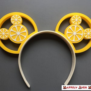May include: Yellow Minnie Mouse ears headband with a lemon design. The ears are shaped like lemons with white lemon slices inside.