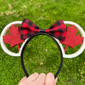 May include: White headband with red and black plaid bow and red felt maple leaf cutouts.