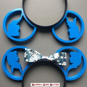 May include: Blue Mickey Mouse ears with a snowflake patterned bow. The ears feature a silhouette of Elsa and Anna from the movie Frozen.
