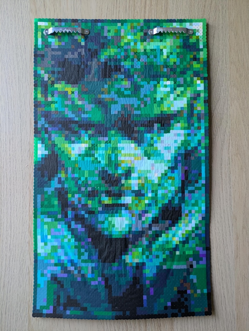 May include: A pixel art mosaic depicting a face with a green, blue, and black color scheme.