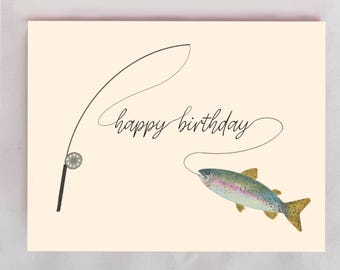 May include: A cream-colored greeting card featuring a black line drawing of a fishing rod and reel. The text "happy birthday" is written in a black cursive script, and a colorful watercolor illustration of a trout is attached to the fishing line.