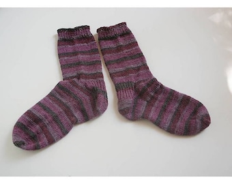 May include: A pair of striped socks in shades of purple and gray. The socks are knitted and have a ribbed texture.