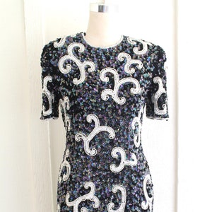 Peut inclure: Une robe noire à paillettes avec un motif de tourbillon blanc. Les paillettes ont une finition irisée.