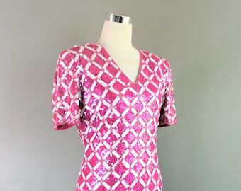 May include: A pink and white sequined dress with a diamond pattern. The dress has short sleeves and a V-neck.