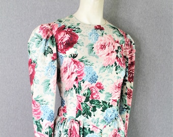 May include: A long-sleeved dress with a floral print featuring pink, blue, and green roses on a cream background. The dress has a fitted bodice and a full skirt.