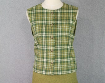 May include: A vintage two-piece outfit on a mannequin. The sleeveless top features a green and white plaid pattern with gold-colored buttons. The skirt is a solid olive green color, creating a coordinated ensemble.