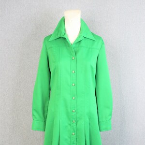 May include: A long-sleeved, green button-down dress with a collared neckline and a flared skirt.