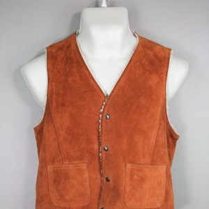 May include: A brown suede vest with a sherpa lining and two front pockets. The vest has a button closure.