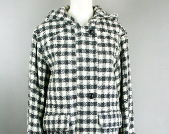May include: A long coat with a hood, featuring a black and white check design. It has a button closure, two pockets, and turned-up cuffs. The coat is displayed on a mannequin.