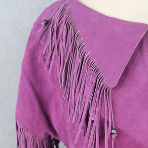 May include: A purple suede jacket with fringe detailing on the collar and sleeves.