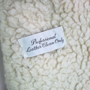 May include: White fabric with a white tag that reads "Professional Leather Clean Only".