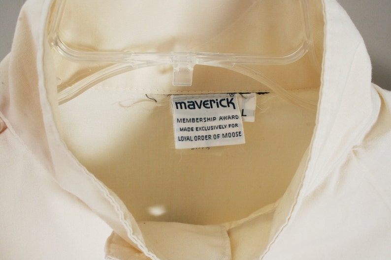 Puede incluir: Camisa blanca con una etiqueta que dice "Maverick Membership Award Made Exclusively for Loyal Order of Moose".