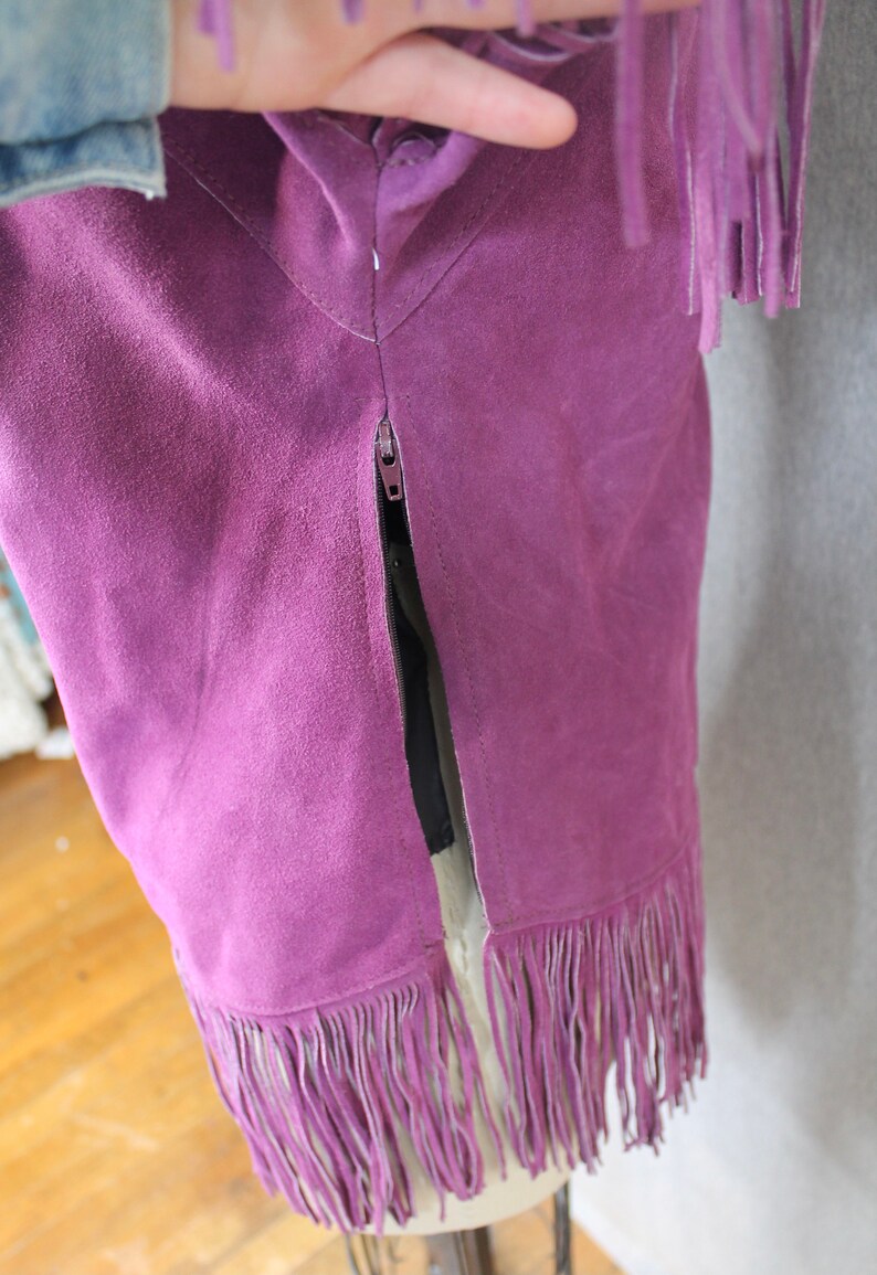 May include: Purple suede skirt with fringe trim and a zipper down the back.