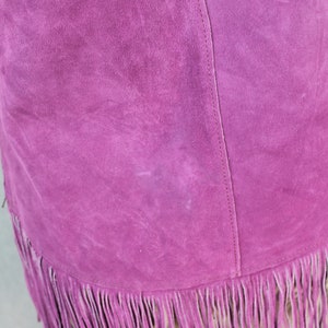 May include: A purple suede skirt with a fringe hem. The skirt has a seam down the back.