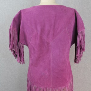 May include: A purple suede top with fringe detailing on the sleeves and hem.
