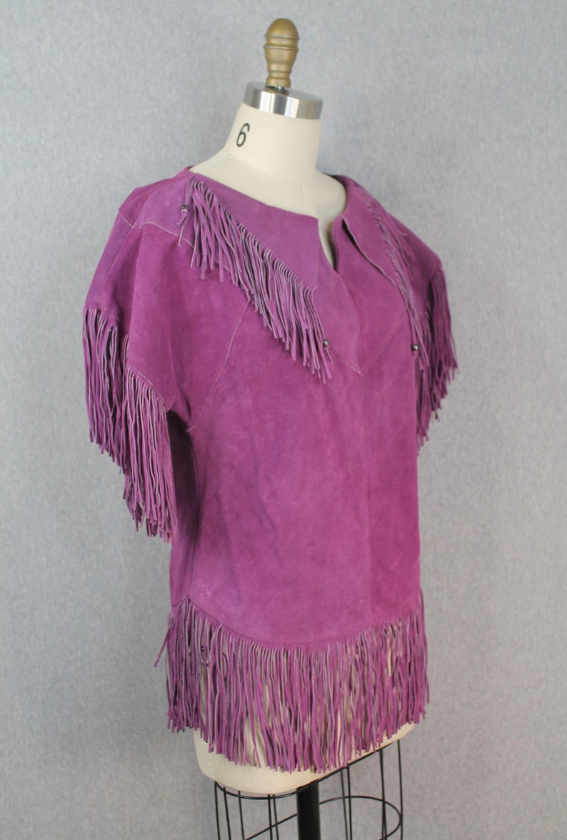 May include: Purple suede jacket with fringe detailing on the collar, sleeves, and hem.