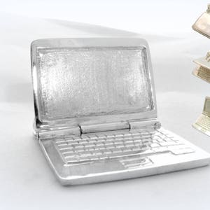 May include: A silver laptop charm with a detailed design, including a keyboard and screen. The charm is a miniature replica of a laptop computer.