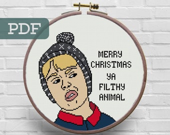 May include: A cross-stitch pattern featuring a cartoon character wearing a black beanie and red and blue clothing. The text "Merry Christmas ya Filthy Animal" is written in white.