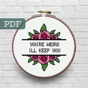 May include: Cross stitch pattern featuring a floral design with pink roses and green leaves. The text "You're Weird I'll Keep You" is displayed in black letters.