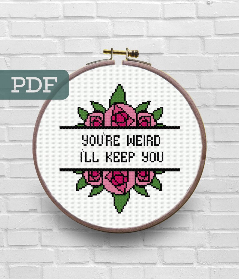 May include: Cross stitch pattern featuring a floral design with pink roses and green leaves. The text "You're Weird I'll Keep You" is displayed in black letters.