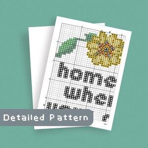 May include: A cross-stitch pattern featuring a yellow flower with a green stem and the text "home where the heart is".