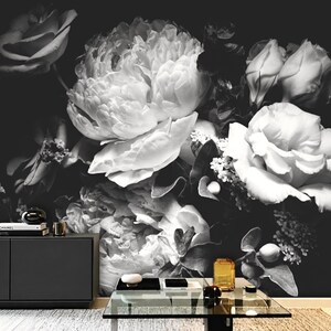 Può includere: Carta da parati floreale in bianco e nero con una grande composizione di peonie e rose. L'immagine ha un contrasto elevato, con i fiori in tonalità di bianco e grigio su uno sfondo scuro. Il murale crea un'estetica drammatica ed elegante.