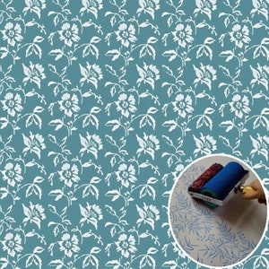 Op de afbeelding: Een blauwe en witte bloemenpatroon rollerstencil voor het schilderen van muren of meubels. De stencil wordt getoond in gebruik met een verfroller op een wit oppervlak.