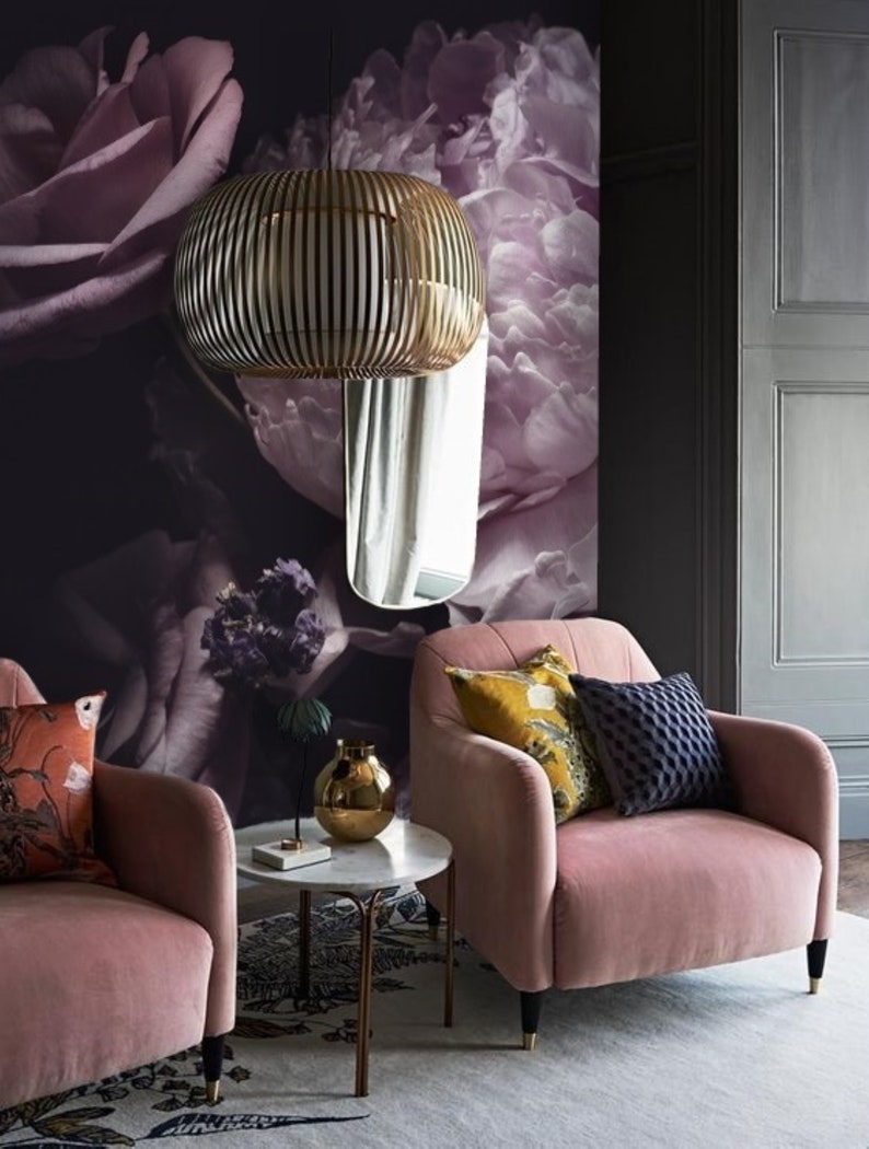 Puede incluir: Dos sillones de terciopelo rosa con almohadas, una mesa auxiliar redonda de m&aacute;rmol blanco con patas doradas y un jarr&oacute;n dorado sobre la mesa. Los sillones est&aacute;n frente a una pared con un papel tapiz floral con grandes peon&iacute;as y rosas rosas.