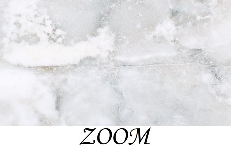 May include: A close-up of a white marble surface with a subtle gray veining pattern. The surface has a smooth, polished texture.