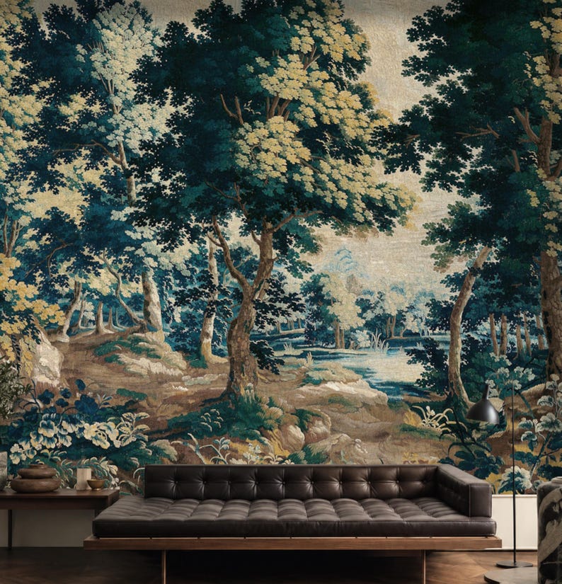 Antique 17th Century forest tapestry wallpaper mural in rich deep blue, muted green, and warm earthy tones, featuring mature trees, lush woodland foliage, delicate wildflowers, and a tranquil stream, styled in a sophisticated living room with a dark leather sofa, warm wood furnishings, and sculptural lighting to create an immersive, timeless focal wall for homeowners or renters seeking an elegant old-world-inspired room makeover.