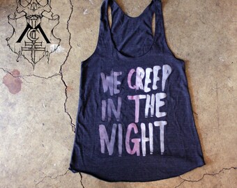May include: A dark gray tank top with a white and pink graphic print that says "We Creep in the Night".