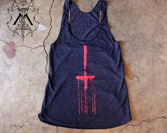 May include: A dark gray tank top with a red upside-down cross graphic. The cross is dripping with red paint.