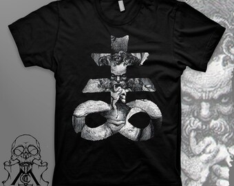 May include: Black t-shirt featuring a detailed, grayscale graphic of a cross-like symbol with a face and figures. The design is intricate and artistic, with a skull and logo on the bottom left. The shirt is a classic crew neck.