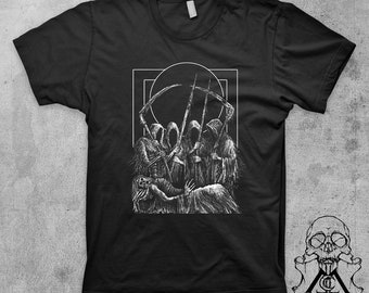 May include: Black t-shirt with a white graphic print of multiple figures in hooded robes holding scythes and standing over a figure lying on the ground. The graphic is framed by a white rectangle.