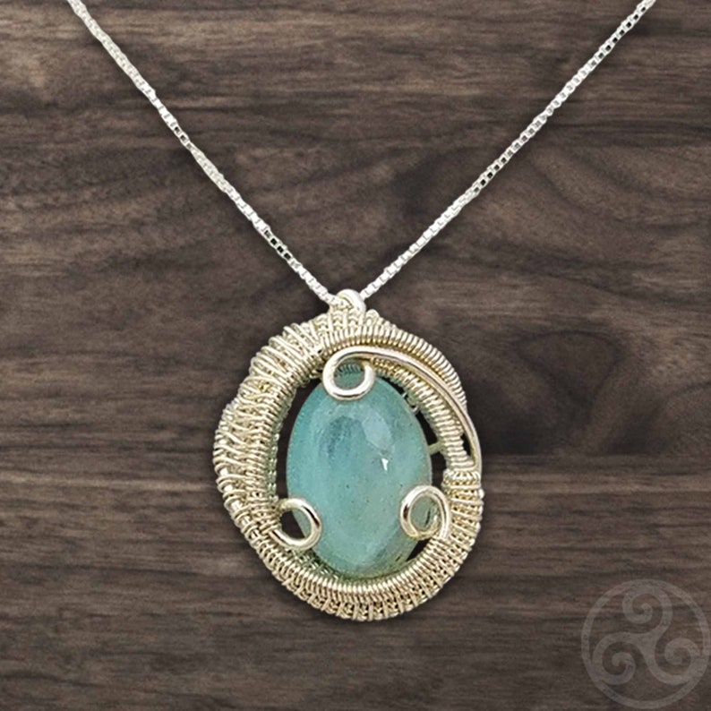 May include: A silver wire wrapped pendant necklace featuring a light blue oval gemstone.