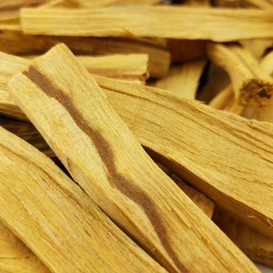May include: A close-up of a pile of light brown palo santo sticks. The sticks have a natural, wood grain pattern and are ready to be burned for their fragrant aroma.