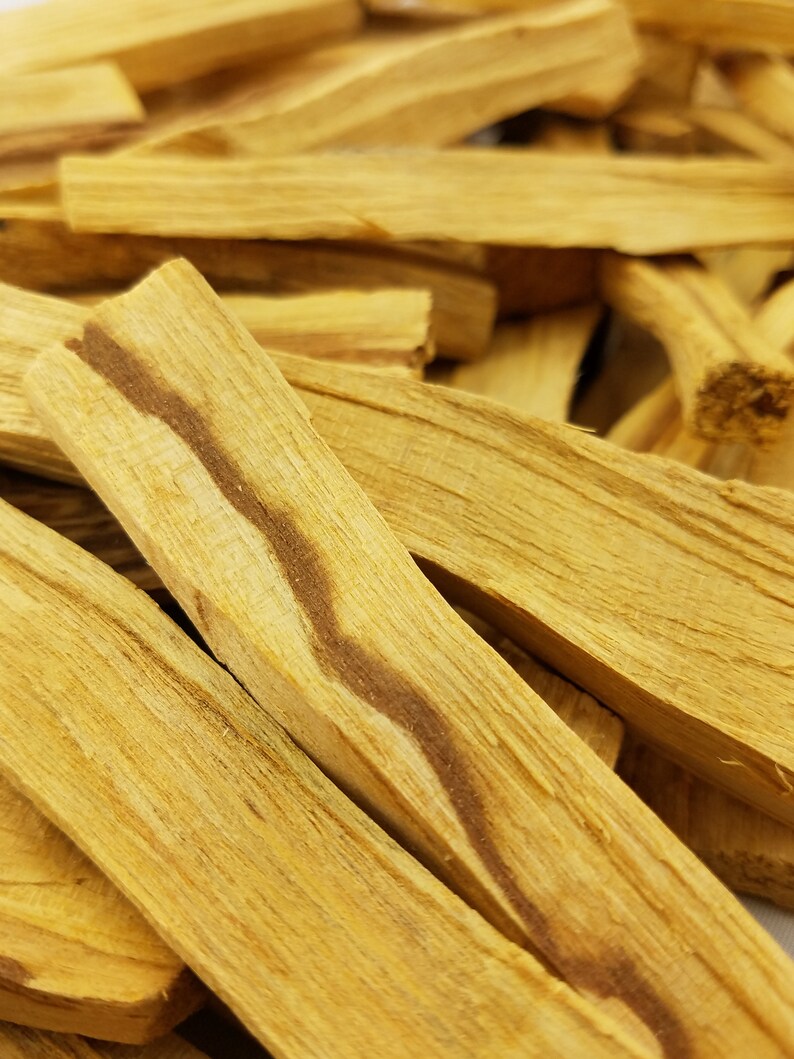 May include: A close-up of a pile of light brown palo santo sticks. The sticks have a natural, wood grain pattern and are ready to be burned for their fragrant aroma.
