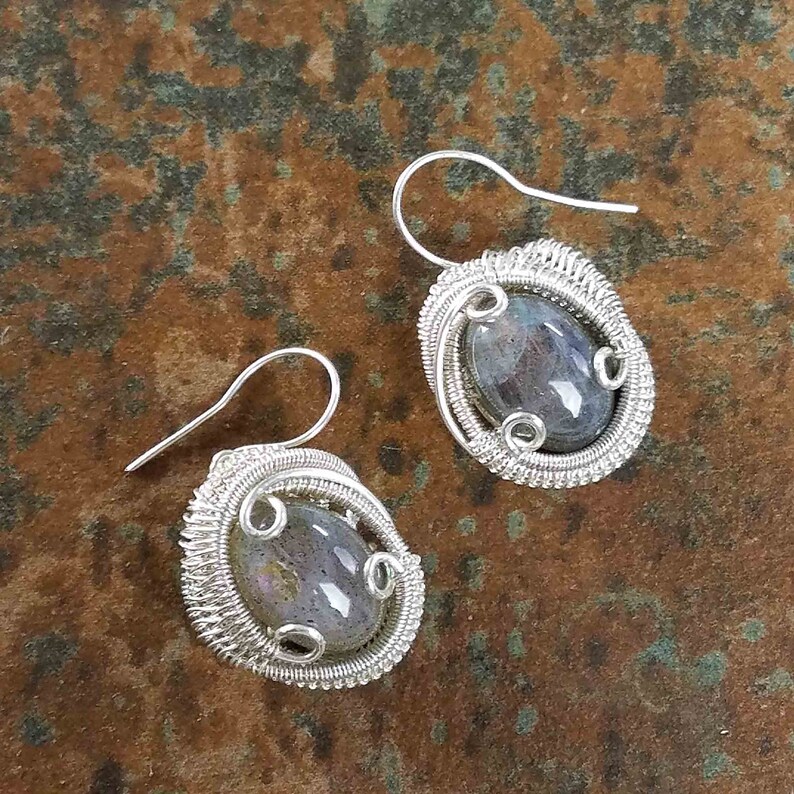 May include: A pair of silver wire wrapped earrings with iridescent gray labradorite stones.