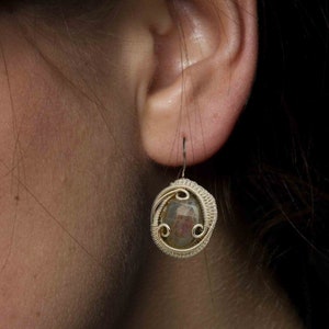 May include: Silver wire wrapped earrings with a dark gray gemstone. The earrings are dangling and have a simple design.