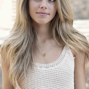 May include: A silver chain necklace with a gold oval pendant featuring a yellow gemstone.