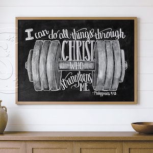 May include: A rectangular wall art piece featuring a black chalkboard background with a white illustration of a dumbbell and the text I can do all things through CHRIST WHO strengthens ME - Philippians 4:13, framed in a light wood border.