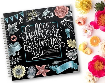 May include: A spiral bound book with a black cover featuring a chalk art illustration of the words "chalk art & lettering 101". The book title is written in a whimsical font with colorful accents. The cover also includes a variety of chalk art illustrations, including flowers, stars, and arrows.