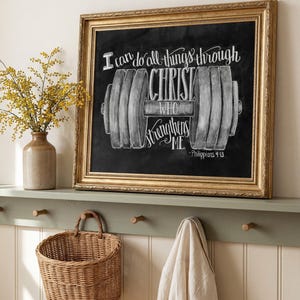 May include: A framed chalkboard art piece with gold trim, featuring the text "I can do all things through Christ who strengthens me" and a dumbbell illustration. A wicker basket and a vase with yellow flowers are also visible.