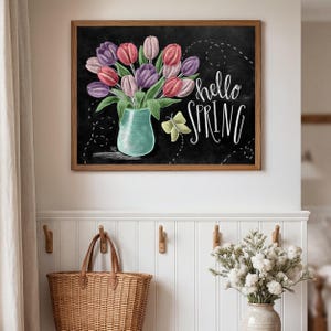 Puede incluir: Un cuadro decorativo en pizarra con un ramo de tulipanes rosas, morados y blancos en un jarr&oacute;n turquesa. La inscripci&oacute;n "hello SPRING" est&aacute; en blanco, con una mariposa amarilla. El marco es de madera.