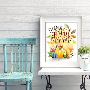 May include: A framed watercolor print with the text "Thank gourd it's fall" in a handwritten font. The print features a yellow gourd, a blue gourd, and a small green gourd surrounded by fall leaves and cotton bolls.