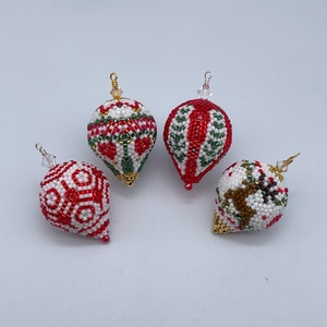 以下が含まれることがあります： ビーズでできた手作りクリスマスオーナメント4つ。オーナメントは赤、白、緑で、それぞれ異なる模様が施されています。1つのオーナメントにはトナカイのデザインが施されています。
