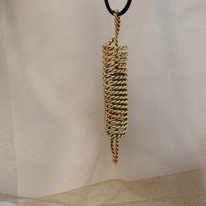 May include: A gold-colored metal pendant in the shape of a spiral, hanging from a black cord.
