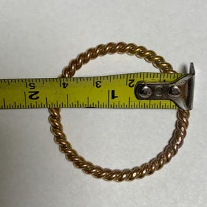 May include: A gold-toned, twisted metal ring measuring 2 inches in diameter.