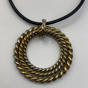 May include: A gold and silver twisted rope pendant necklace with a black cord.